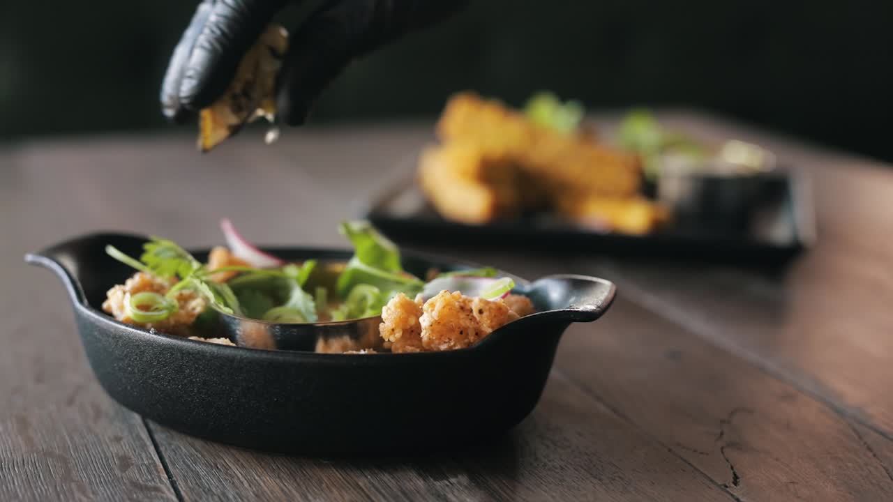 chefs mano exprimiendo un limón sobre un plato con marisco y hierbas