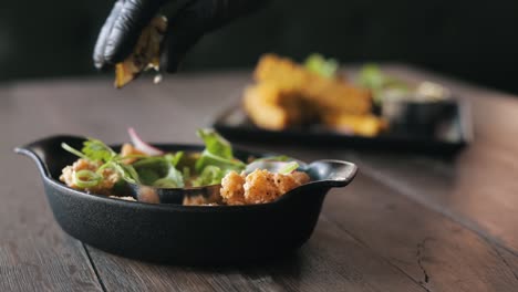 chefs hand squeezing a lemon over a dish with sea food and herbs