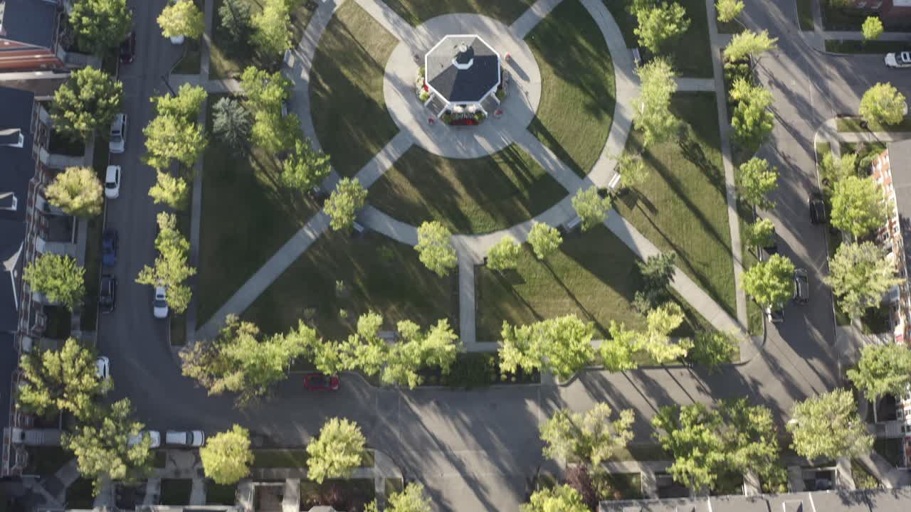 vista de pájaro volar sobre la réplica del suburbio de inverness hay una isla en el centro de la calle residencial que conduce a la plaza comunitaria exuberante parque con mirador en el centro durante el amanecer de verano 5-5