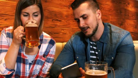 Pareja-Usando-Teléfono-Móvil-Mientras-Toma-Un-Vaso-De-Cerveza