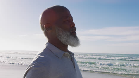 senior african american man standing at the beach, admiring the view, closing eyes