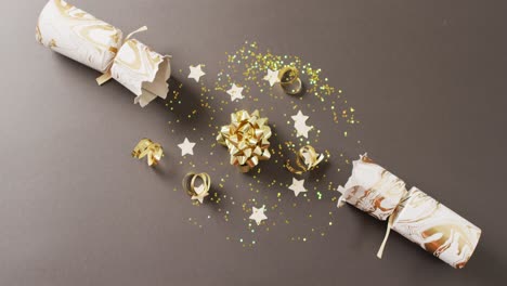 Video-of-christmas-crackers,-stars-and-decoration-on-grey-background