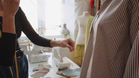 dressmaker and female client trying on shirt in sewing studio