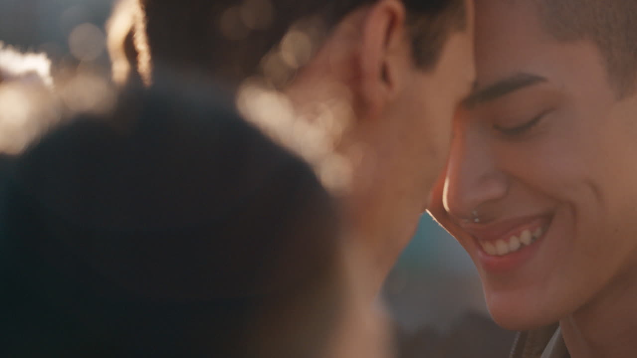 슬로우 모션 젊은 동성애 커플이 함께 춤을 추고 해가 지는 날 옥상 파티를 즐기고 친밀한 연결을 공유하고 친구 그룹이 즐겁게 여름 휴가를 축하합니다.