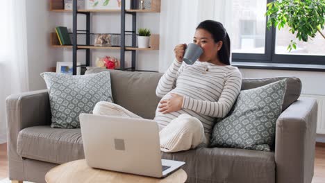 Glückliche-Schwangere-Asiatische-Frau-Mit-Laptop-Zu-Hause.Schwangerschaft,-Ruhe,-Menschen-Und-Erwartungskonzept-Glücklich-Lächelnde-Schwangere-Asiatische-Frau-Mit-Laptop-Computer-Sitzt-Auf-Dem-Sofa-Zu-Hause