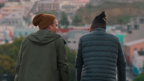 happy friends chatting on rooftop enjoying converation hanging out sharing view of beautiful city skyline at sunset