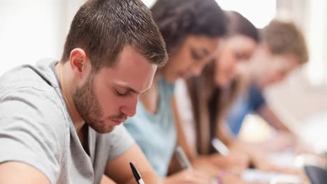 Animación-De-Estudiantes-Concentrándose,-Sentados-Escribiendo-En-El-Aula.