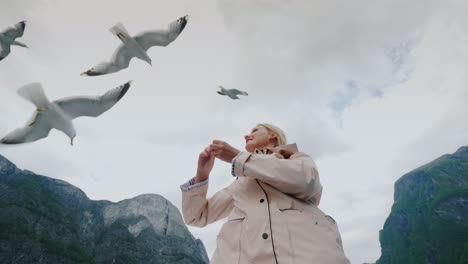 Eine-Frau-Füttert-Eine-Möwe,-Die-Im-Vertrauen-Fliegt-Und-Die-Konzeptreise-Durch-Die-Fjorde-Von-Nor-Zähmt