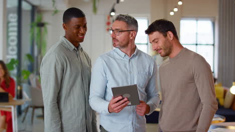 Male-Multi-Cultural-Business-Team-With-Digital-Tablet-In-Modern-Open-Plan-Office