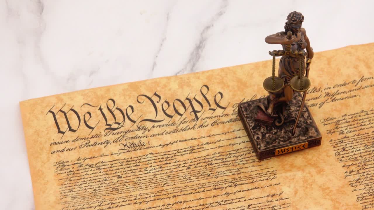 A powerful symbol of law and democracy, the Statue of Justice stands prominently before the United States Constitution, representing fairness, balance, and the rule of law