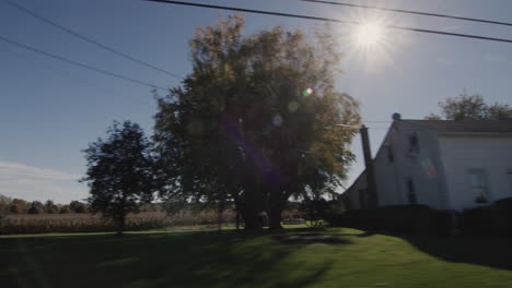 drive along a typical agricultural region in the u.s. the sun illuminates houses and fields