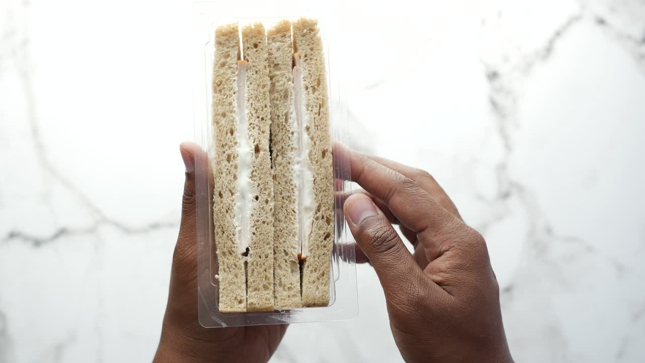 포장 된 샌드위치를 들고 있는 손