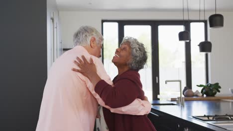 Happy-senior-diverse-couple-dancing-in-kitchen-at-retirement-home