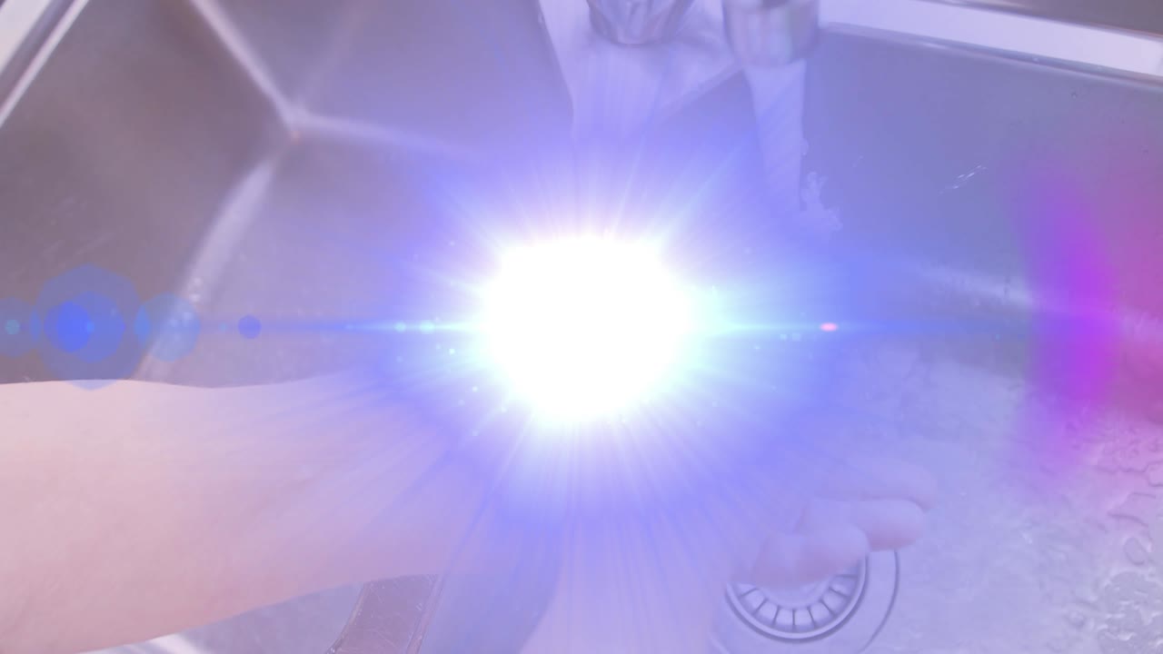 주방 싱크대에 손을  ⁇ 고 있는 고령 여성의 손 위로 움직이는 빛의 애니메이션