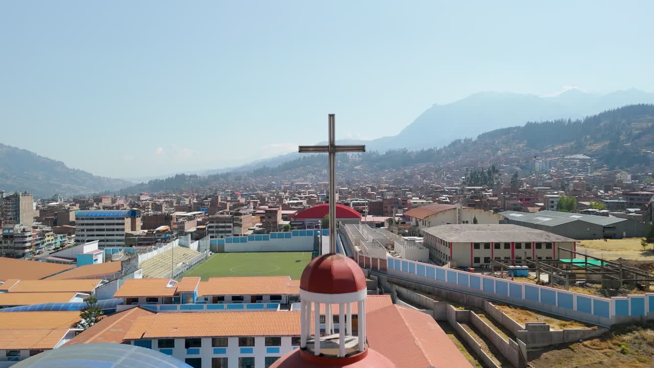 A beautiful aerial shot ascends past the bell tower and cross of the historic Iglesia San Francisco, revealing the Huaraz cityscape and Andes mountains in the background