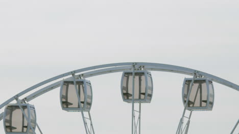 Spinning-Ferris-Wheel-With-Glass-Cabin-Against-Gloomy-Sky