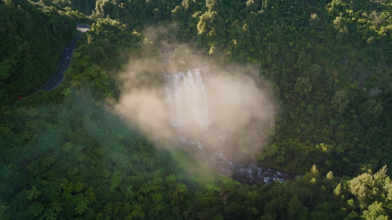 뉴질랜드의 해가 뜨는 동안 구름을 통해 떠다니며 마로코파 폭포를 드러 ⁇ 니다.