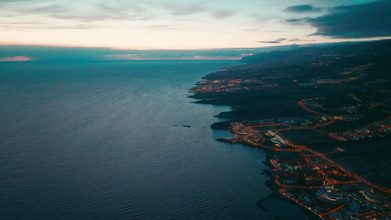 hermosa costa iluminada por las luces de la ciudad costera en el crepúsculo al atardecer