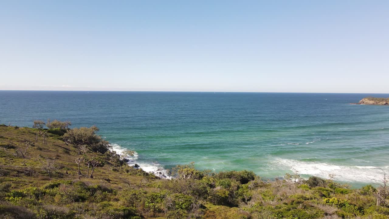 Drone rises over treetops to reveal brilliant blue ocean in Noosa National Park