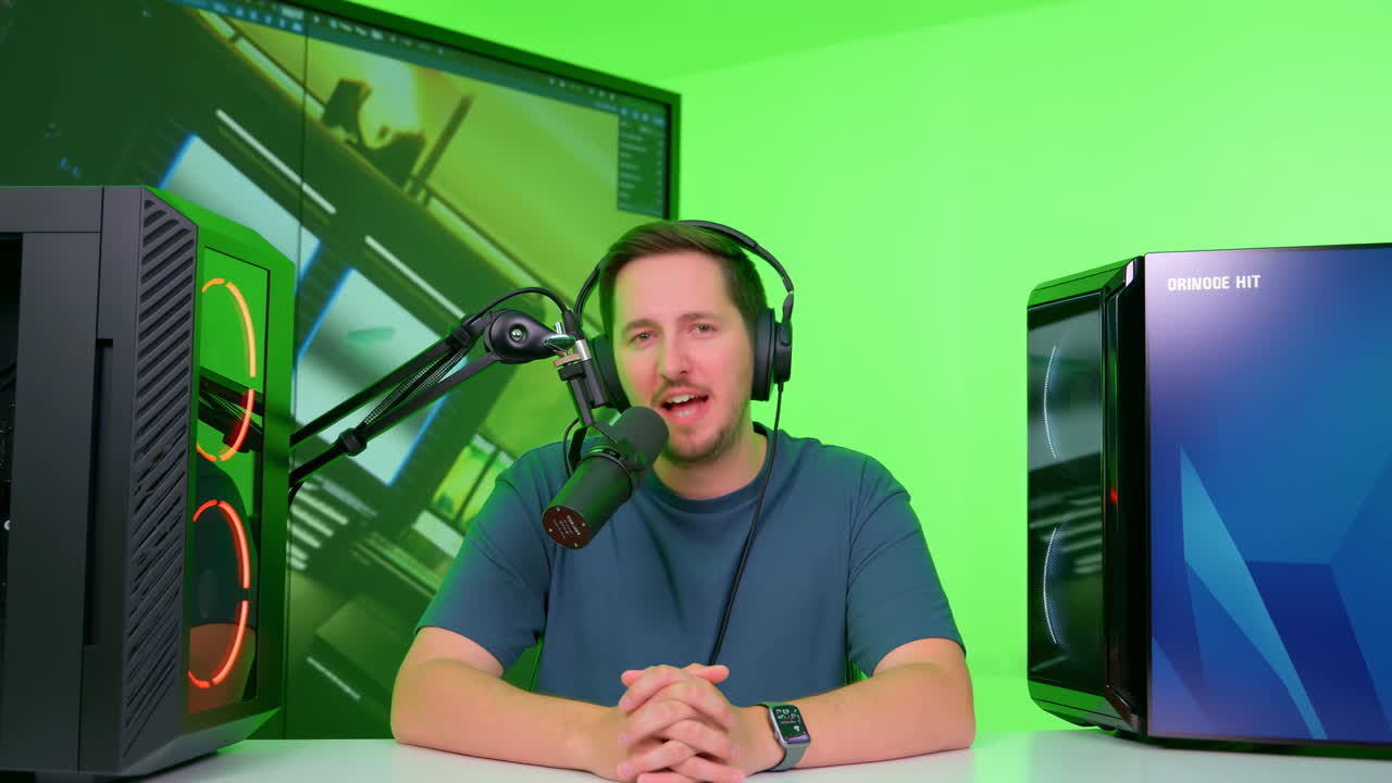 Host di podcast uomo, scrivania con green screen, parla in microfono montato con cuffie, mani giunte, affiancato