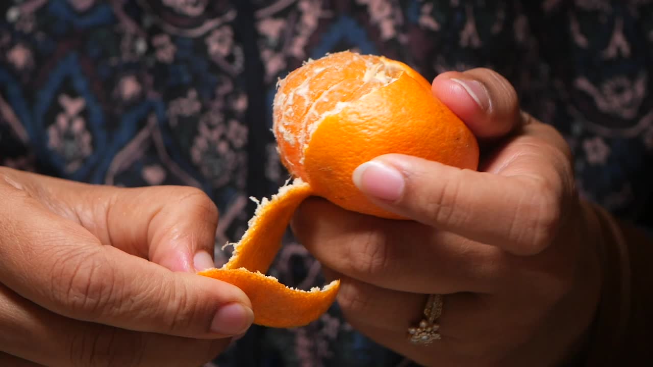 Close-up de Mãos Descascando uma Laranja Fresca.