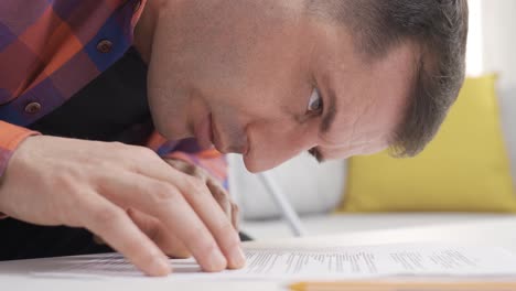 el hombre con discapacidad visual está tratando de leer el periódico en la mesa.