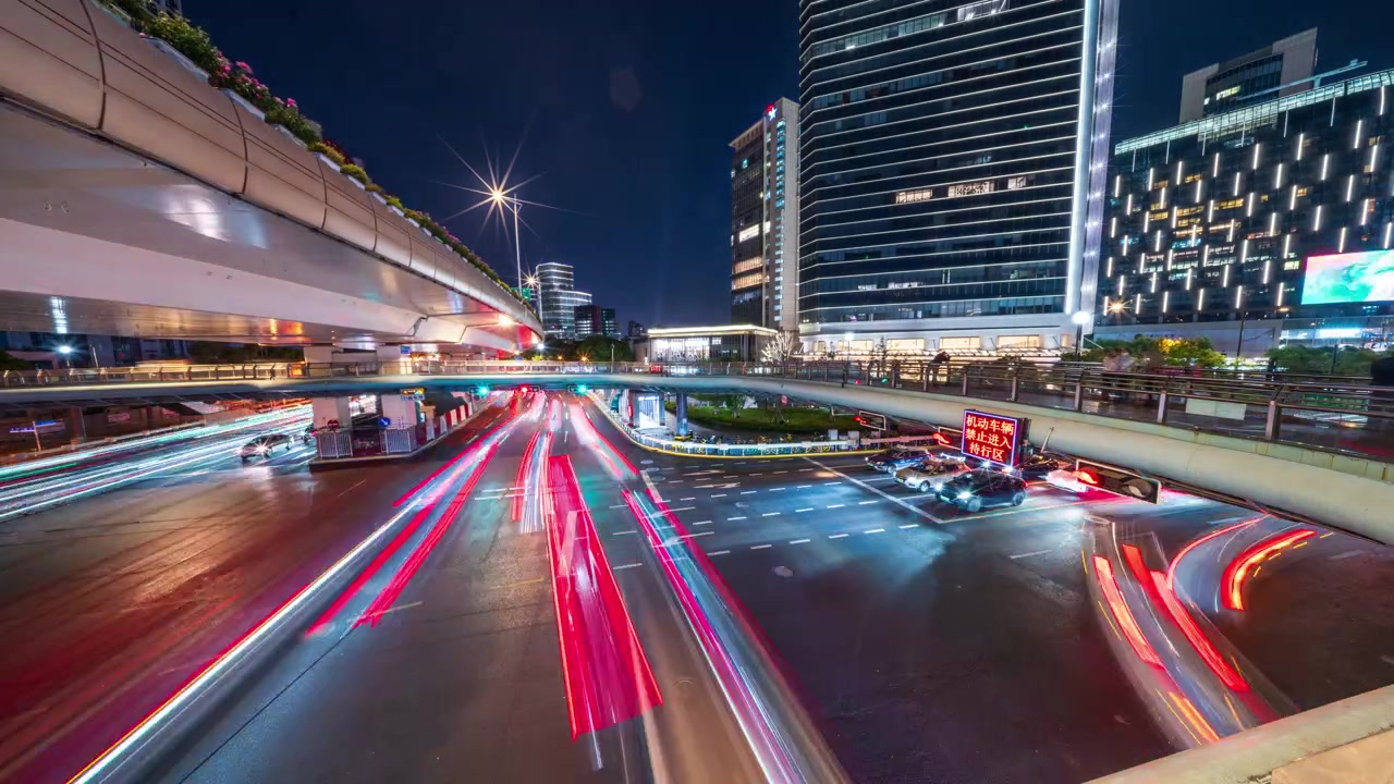 Urban traffic flows beneath elevated roads at night, surrounded by modern high-rises