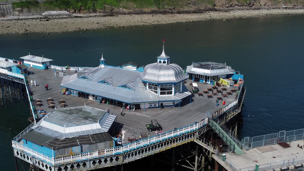 Vista aerea con zoom in sul pontile di Llandudno, località balneare, padiglione d'argento simbolo, passerella in legno.