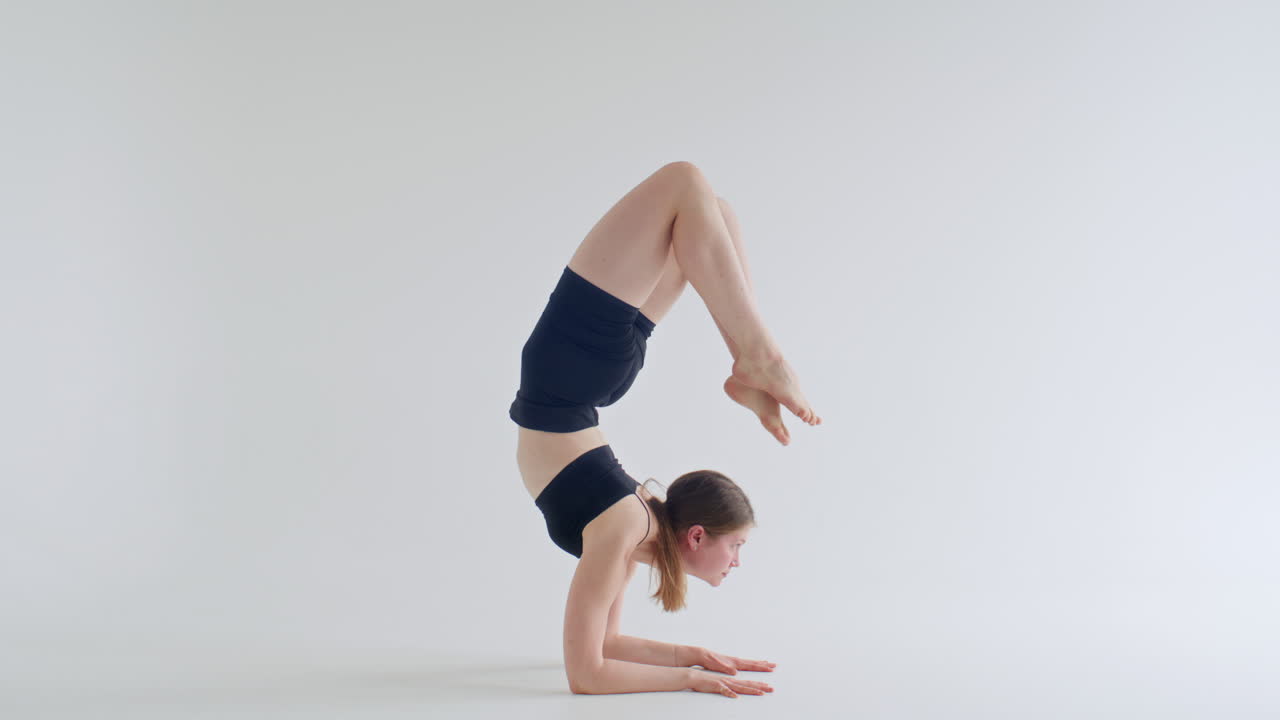 Junge Frau in Skorpion-Pose beim Yoga in einem minimalistischen Studio