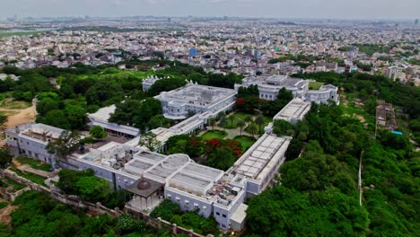 top down drone view of falaknuma palace with trees and crowded residence buildings at engine bowli, falaknuma, hyderabad, telangana, india. day time, semi orbit, drone shot, 4k.