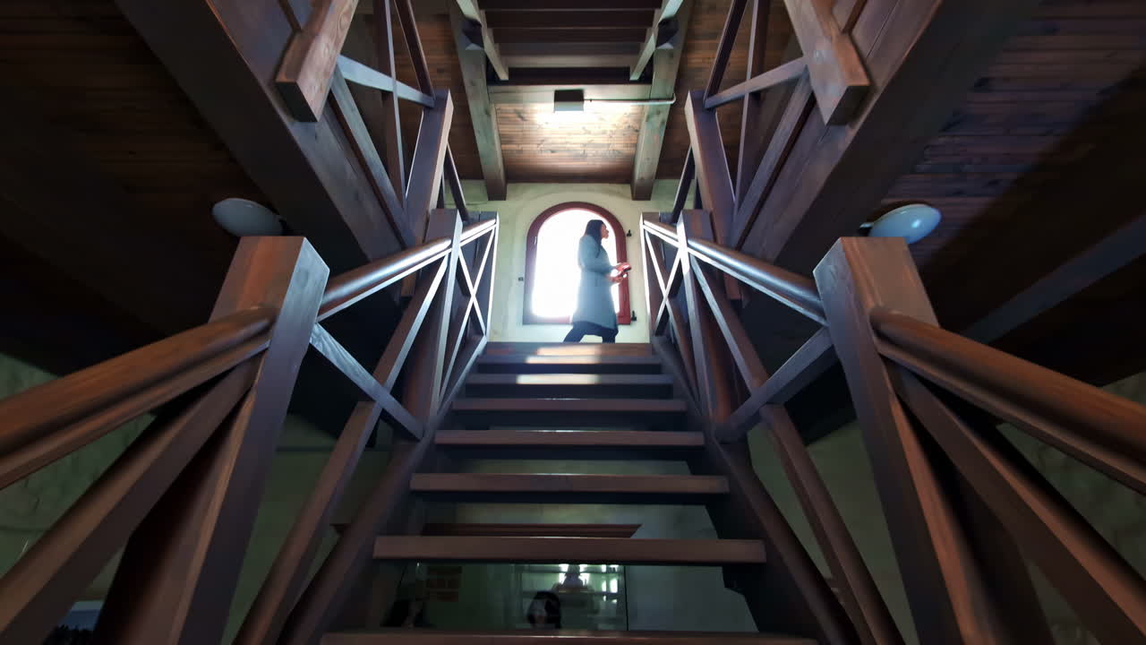 Capturing a serene slow-motion ascent up wooden stairs toward a radiant sunlit window