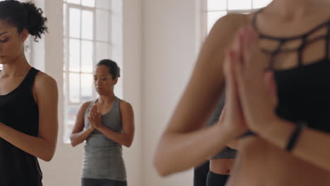 beautiful caucasian yoga woman practicing warrior pose meditation with group of multiracial women enjoying healthy lifestyle exercising in fitness studio at sunrise