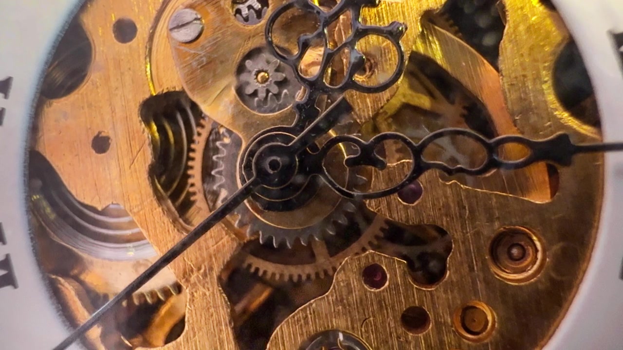 Macro Close Up of Old Wind-Up Pocket Watch Internal Clockwork Components. Gears turn and tick as the second hand rotates at its base.