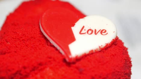 red velvet heart-shaped cake with "love" inscription