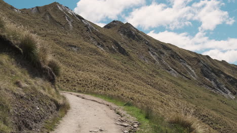 peaceful new zealand hiking trail with mountains blue sky and clouds in the background