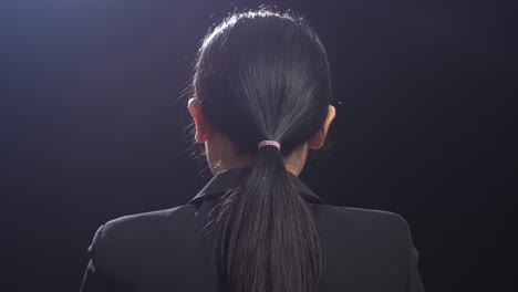 back view of asian speaker woman in business suit speaking in the black screen studio