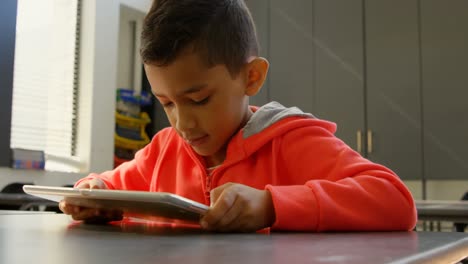 Front-view-of-attentive-Asian-schoolboy-studying-with-digital-tablet-in-classroom-at-school-4k