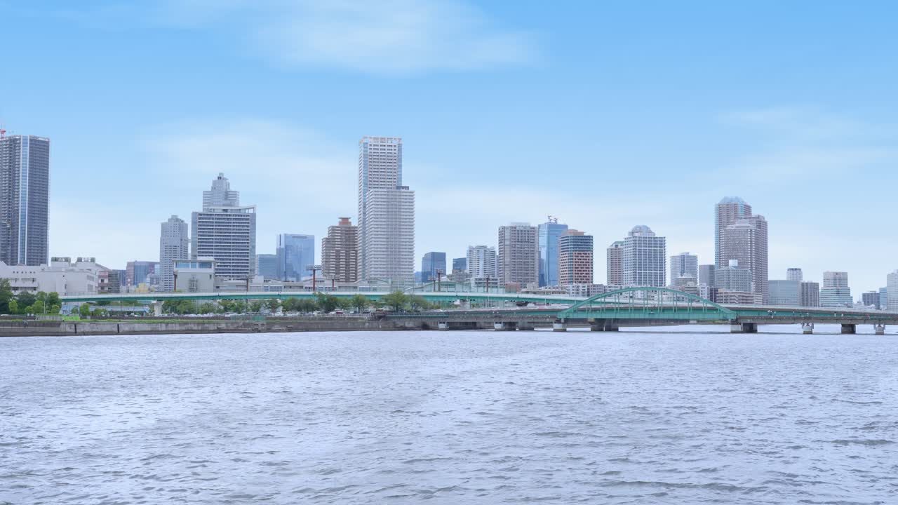 A wide, peaceful shot of the expansive Tokyo Bay with the distant cityscape and a bright sky