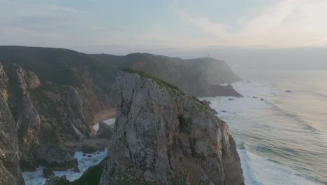 Aerial-revealing-shot-of-Ursa-Beach-in-Portugal-with-reaching-waves-between-rocks-and-cliffs