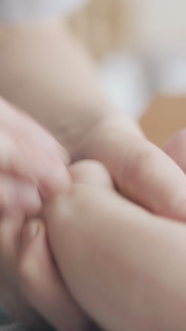 skilled nurse performs hypertonus leg massage professionally and holds newborn boy little foot extreme close view