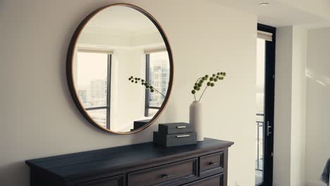 a circular mirror, black dresser, and modern decorations in a bedroom of a home