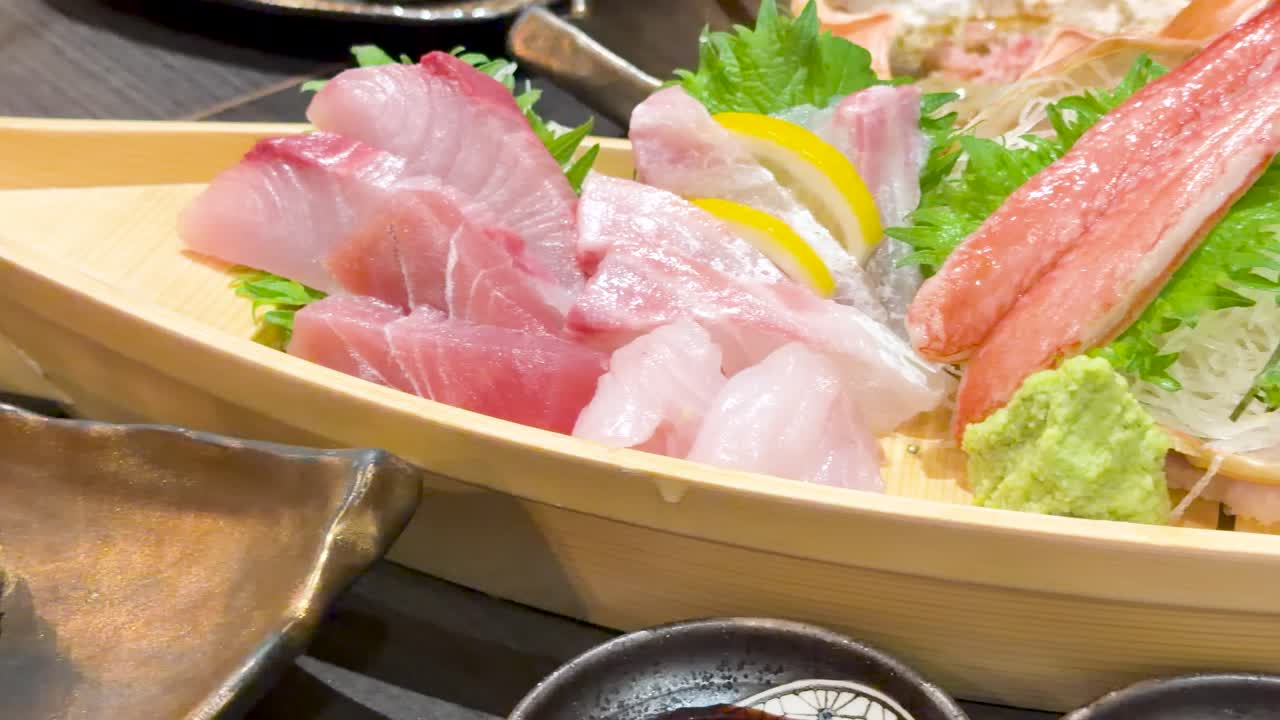 Inquadratura ravvicinata a mano di pesce crudo fresco, granchio e guarnizioni in un ambiente da ristorante.