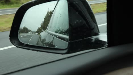 el reflejo de un viaje en una carretera lluviosa en el espejo lateral