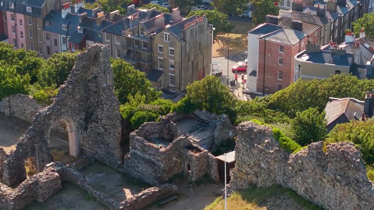 Lange neerwaartse boog van de ruïnes van Hastings Castle creëert een parallax-effect, waardoor de moderne winkels en straten erachter zichtbaar worden