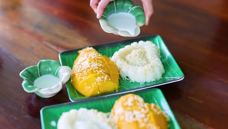 pouring coconut milk over mango sticky rice