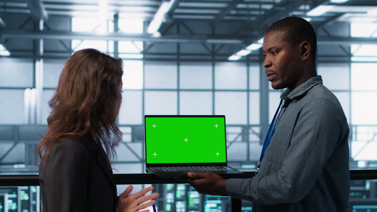 Technicians in data center using green screen mockup laptop