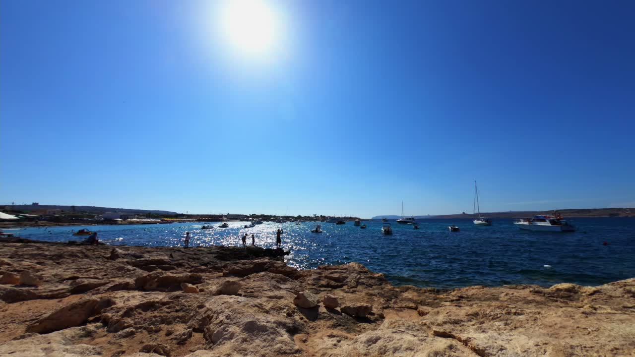 몰타, 리틀 아미어 베이, 화창한 여름 오후에 낚시꾼과 해수욕객이 있는 해변에서 시간 경과 비디오