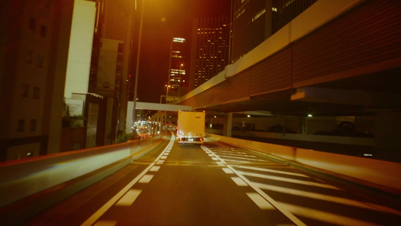Guida notturna sull'autostrada di Tokyo con le luci della città.
