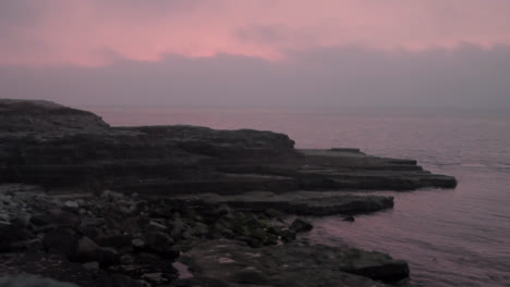 a beautiful sunrise scene at the bill in portland, england, casting an orange color in the air