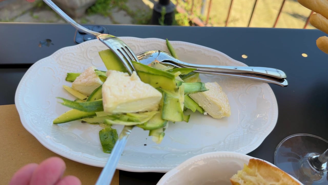 Primo piano di una persona che usa la forchetta per mangiare un'insalata vegetariana sana durante un pranzo all'aperto